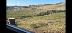 a view from a window of a field with a mountain at Eco Crofter's Wagon by the Sea - Off Grid Experience - No electricity - As seen soon on Netflix in Oldshoremore