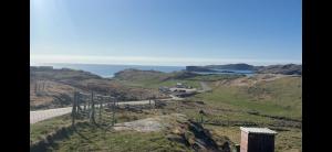 a view of a hill with the ocean in the background at Eco Crofter's Wagon by the Sea - Off Grid Experience - No electricity - As seen soon on Netflix in Oldshoremore