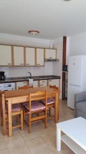 eine Küche mit einem Holztisch und Stühlen sowie eine Küche mit einem Kühlschrank in der Unterkunft Vivienda Amanecer in Los Cancajos + 6 Fotos