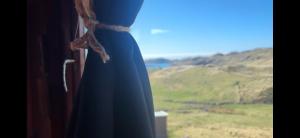 a blue dress on a window with a view at Eco Crofter's Wagon by the Sea - Off Grid Experience - No electricity - As seen soon on Netflix in Oldshoremore