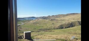 a view from a train window of a field and mountains at Eco Crofter's Wagon by the Sea - Off Grid Experience - No electricity - As seen soon on Netflix in Oldshoremore