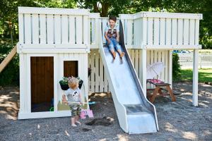dwójka dzieci wspina się na zjeżdżalnię na domku zabaw w obiekcie Danhostel Horsens w mieście Horsens