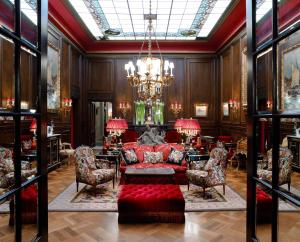 a living room with a red couch and chairs at Hotel Sacher Wien in Vienna