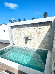 una piscina con un muro di pietra e un lavandino di Premium Casa Maragogi Japaratinga a Japaratinga