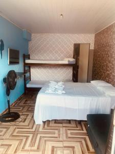 a hotel room with a bed and a fan at kitnet aconchegante in Ubatuba