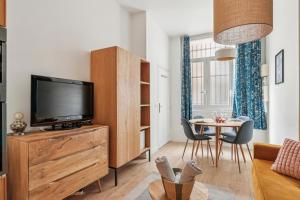 Il comprend un salon doté d'une télévision et d'une table avec des chaises. dans l'établissement L'Oasis Rouennais - Hypercentre - Gare rive Gauche, à Rouen