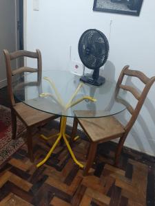 a glass table with a fan and two chairs at Apartamento completo temporada privativo no centro in Porto Alegre