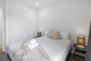 ムールーラバにあるThe Smith Mooloolaba Beach Retreatのタオルが敷かれた白いベッドのある寝室