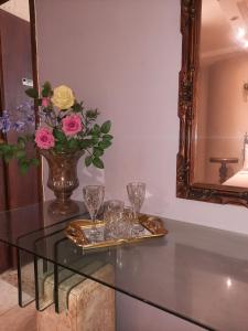 une table en verre avec des verres et un vase avec des fleurs dans l'établissement Luz do Sol Pousada 700m Praia do Peró, à Cabo Frio