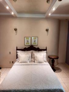 une chambre avec un grand lit avec des oreillers blancs dans l'établissement Luz do Sol Pousada 700m Praia do Peró, à Cabo Frio