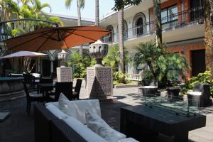 a patio with tables and chairs and an umbrella at TRES79 Hotel Boutique Orizaba in Orizaba