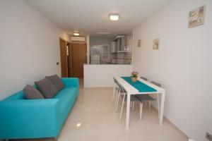 a living room with a blue couch and a table at Apartamentos Maysan in Benidorm