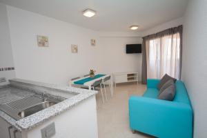 a living room with a blue couch and a kitchen at Apartamentos Maysan in Benidorm