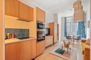 une cuisine avec des placards en bois et une salle à manger dans l'établissement L'Oasis Rouennais - Hypercentre - Gare rive Gauche, à Rouen
