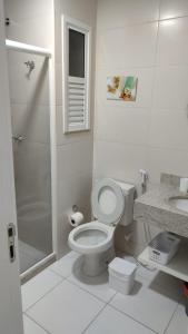 a white bathroom with a toilet and a shower at Alojamiento Arraial Do Cabo Golden Lake in Arraial do Cabo