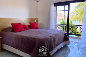 a bedroom with a bed with red pillows and a balcony at Casa super aconchegante em Torres - Piscina - Pátio Privativo - Ar condicionado suíte - TV Smart - Wifi - Em frente a Lagoa do Violão - Aceita Pet in Torres +70 photos