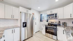 Awesome Two Bedroom Family Upper Unit in Denver في دنفر: مطبخ بخزائن بيضاء وثلاجة من الفولاذ المقاوم للصدأ