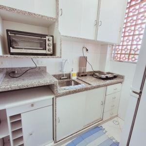 a small kitchen with a sink and a microwave at Apartamento Confortável a 350m da Praia dos Sonhos Itanhaém in Itanhaém +18 photos