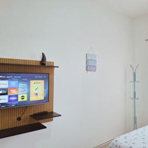 a television in a room with a white wall at Apartamento Confortável a 350m da Praia dos Sonhos Itanhaém in Itanhaém