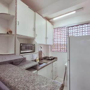 a kitchen with white cabinets and a refrigerator at Apartamento Confortável a 350m da Praia dos Sonhos Itanhaém in Itanhaém