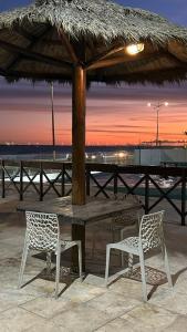 a table and two chairs under a straw umbrella at Apartamento a Beira mar de Maceió in Maceió