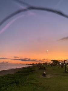 a sunset on the beach with a bench in the foreground at Pousada Beiramar in Rio das Ostras +18 photos