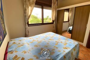 una camera da letto con un letto con un piumone blu e una finestra di Apto 2 quartos na praia de Torres - 500mts do mar - Varanda com churrasqueira - Tv Smart - Wifi - Garagem - Aceita Pet a Passo de Torres