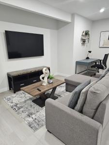 a living room with a couch and a flat screen tv at Brand-New Guesthouse-2bedrooms in Calgary