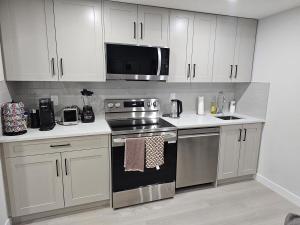 a kitchen with stainless steel appliances and white cabinets at Brand-New Guesthouse-2bedrooms in Calgary
