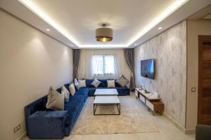 ein Wohnzimmer mit einem blauen Sofa und einem Tisch in der Unterkunft Luxury 2-Bedroom Apartment with Balcony - Heart of Gueliz in Marrakesch