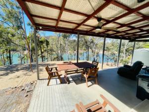 a large deck with a wooden table and chairs at Taylor Bay Cabin in Eildon