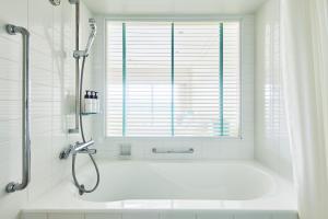 a white bath tub in a bathroom with a window at ANA InterContinental Manza Beach Resort by IHG in Onna