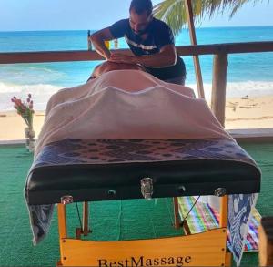 a man is sitting on a bed in front of the beach at Hostal velero relax in Playa Mendiguaca