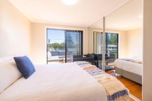a bedroom with a large white bed and a balcony at Robinson Retreat with Beach Bungalow, 3 Robinson St - air con, 2 kitchens, 6 bedrooms, 4 bathrooms in Anna Bay