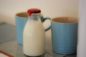 a bottle of milk next to two cups on a counter at Manor Farm Stay in Sutton on Sea
