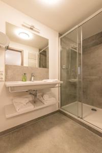 bagno con doccia, lavandino e specchio di Gasthof Chiemseefischer a Grabenstätt