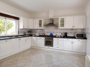 uma grande cozinha branca com armários e electrodomésticos brancos em Villa V4 Filomena em Mosqueira
