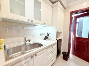 una cucina con mobili bianchi e un lavello di Shanghai downtown Tyms B&B Near Hongqiao Metro and Jiaotong University High view 3bedroom&2bathroom a Shanghai