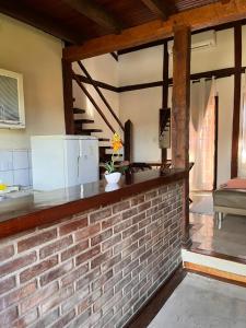 a kitchen with a brick wall with a refrigerator at Pousada Chalés Sinbad in Ilhabela