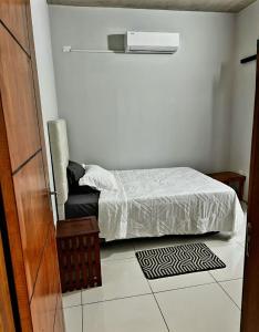 a small bedroom with a bed and a chair at Comodo Dpto bien equipado cerca de Aeropuerto y COP Comité Olímpico Py in Luque