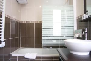 a bathroom with a white tub and a sink at The Originals Boutique, Hôtel d'Angleterre, Le Havre, centre, plage in Le Havre