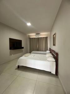 a bedroom with a bed and a flat screen tv at Apartamento 103 - Suíte com ar condicionado in Patos de Minas