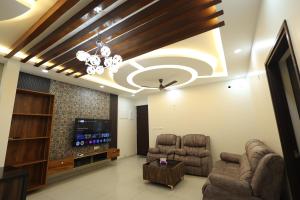 a living room with two chairs and a flat screen tv at Luxury Stay with Outdoor Pool and Gym near Bangalore Airport in Bengaluru