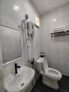 a bathroom with a white toilet and a sink at Reds Roomstay Pantai Penarik 3 in Kampong Ru Sepuloh