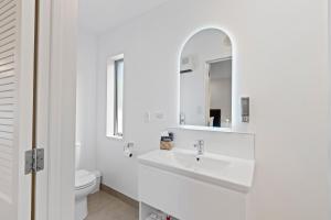 a white bathroom with a sink and a mirror at Tussock Peak Lodge in Hanmer Springs +116 photos