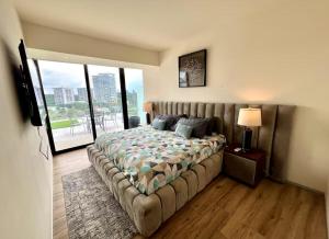 a bedroom with a large bed and a large window at Departamento Deluxe 2H-48 in Guadalajara