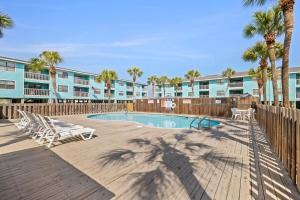 a swimming pool with lounge chairs and palm trees at Vitamin Sea in Gulf Shores
