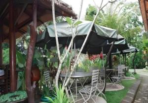 a table and chairs under an umbrella in a garden at KK by Secoms in Yogyakarta