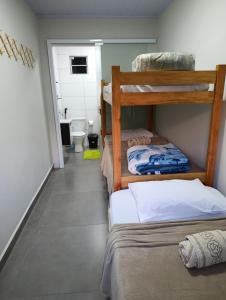 a room with three bunk beds and a bathroom at Kitnet Sol e Lua in Caparaó Velho