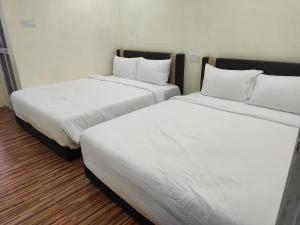 two beds in a room with white sheets and pillows at Reds Roomstay Pantai Penarik 3 in Kampong Ru Sepuloh